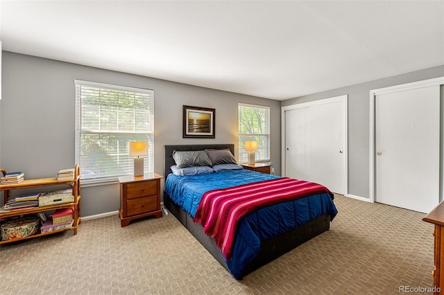carpeted bedroom with multiple closets and baseboards