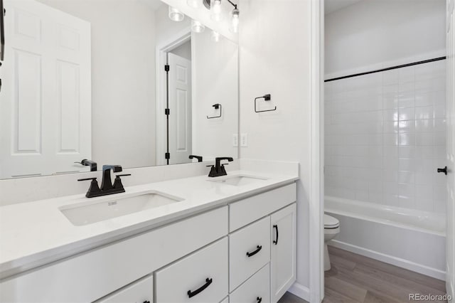 full bathroom featuring hardwood / wood-style flooring, vanity, toilet, and tiled shower / bath