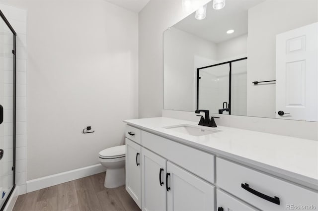 bathroom featuring vanity, wood-type flooring, a shower with door, and toilet