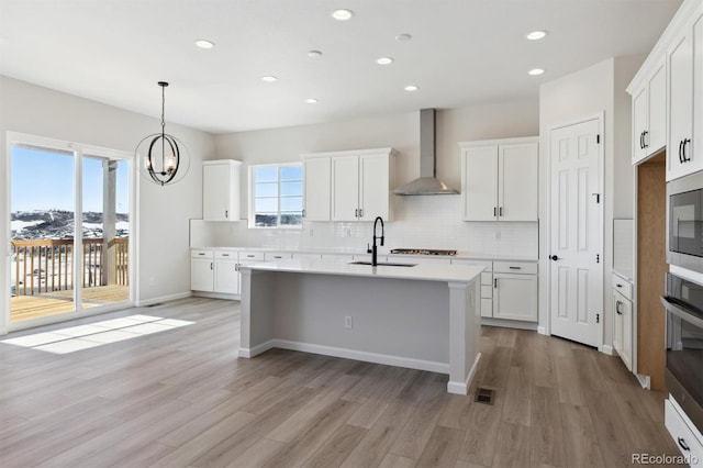 kitchen featuring white cabinetry, stainless steel appliances, sink, and wall chimney range hood