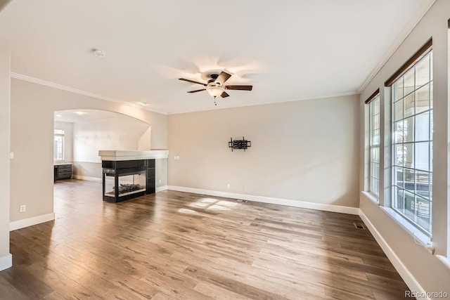 unfurnished living room featuring plenty of natural light, wood-type flooring, ornamental molding, and a fireplace