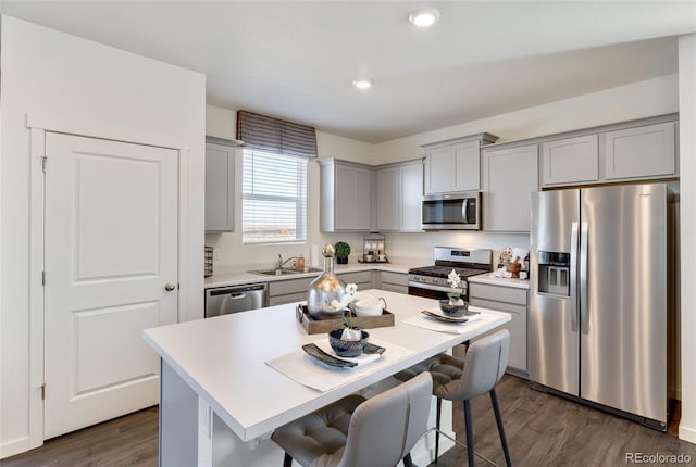 11782 Foraker Ln, Colorado Springs, CO 80925 - kitchen with appliances with stainless steel finishes, gray cabinets, dark wood-style floors, a breakfast bar, and light countertops