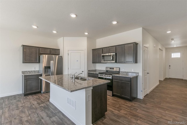 13487 Valentia St, Thornton, CO 80602 - kitchen with appliances with stainless steel finishes, a sink, dark wood finished floors, light stone countertops, and dark brown cabinetry