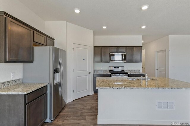 13487 Valentia St, Thornton, CO 80602 - kitchen with stainless steel appliances, a sink, dark wood-style flooring, dark brown cabinets, and a center island with sink