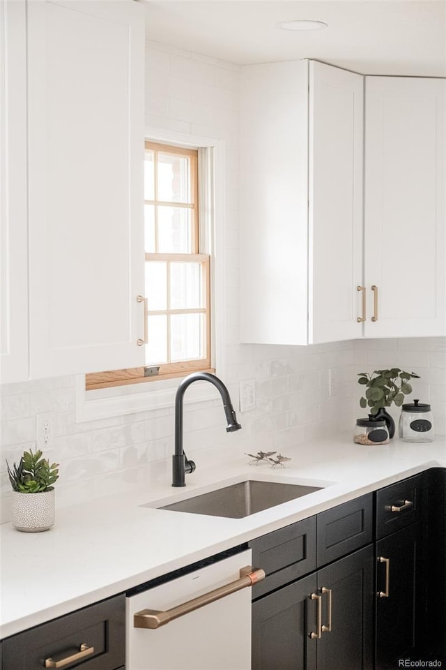 kitchen featuring white cabinetry, dishwasher, sink, and decorative backsplash