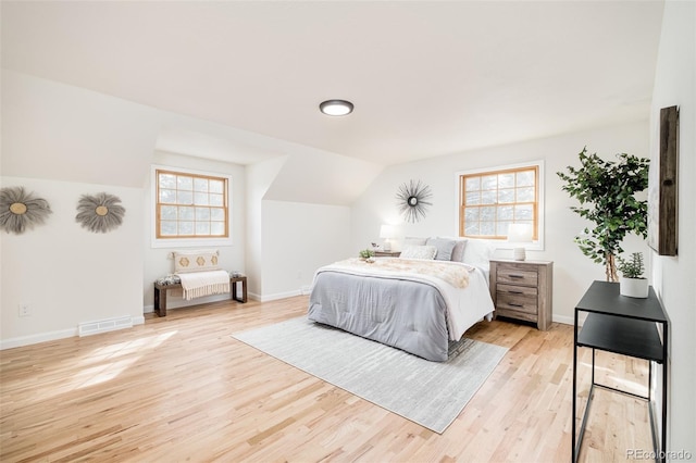 bedroom featuring multiple windows, vaulted ceiling, and light wood-type flooring