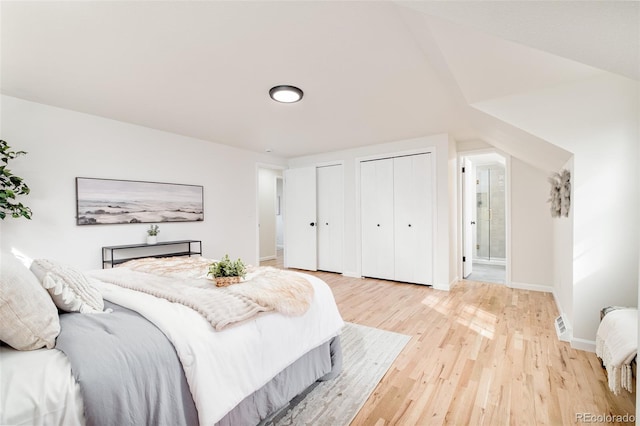 bedroom featuring connected bathroom, two closets, and wood-type flooring