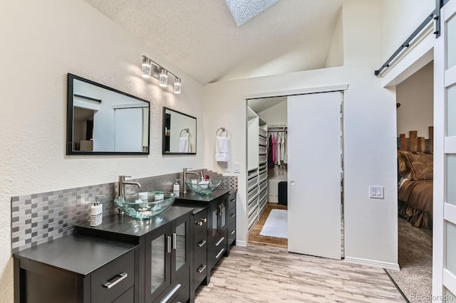 10360 Irving Ct, Westminster, CO 80031 - ensuite bathroom featuring double vanity, vaulted ceiling, wood finished floors, a walk in closet, and tasteful backsplash