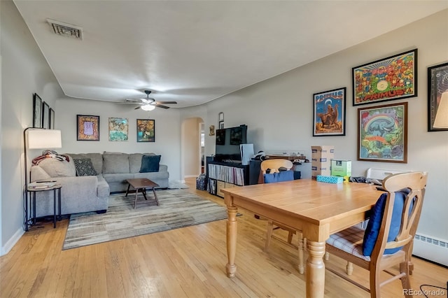 6095 W 47th Ave, Wheat Ridge, CO 80033 - dining room with arched walkways, ceiling fan, light wood finished floors, baseboards, and a baseboard radiator