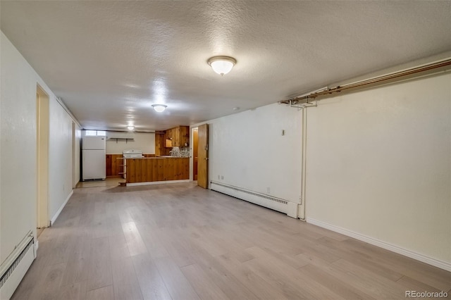 6095 W 47th Ave, Wheat Ridge, CO 80033 - finished basement with a baseboard radiator, freestanding refrigerator, light wood finished floors, a textured ceiling, and baseboards
