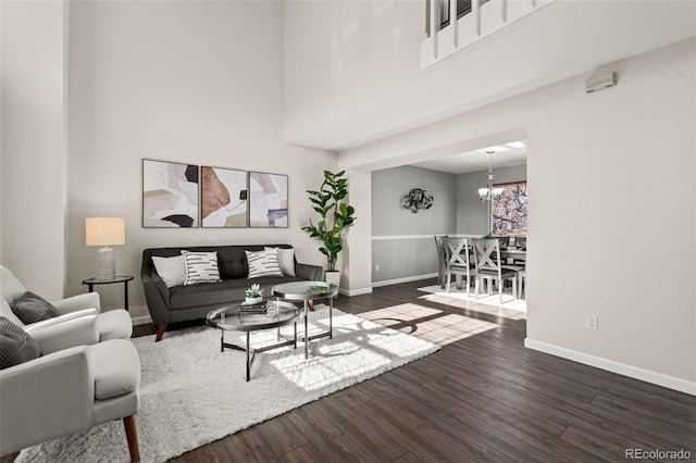 living room with an inviting chandelier, dark hardwood / wood-style floors, and a high ceiling