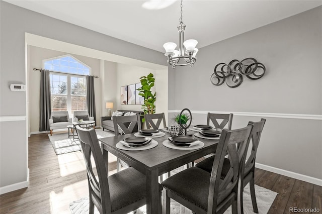 dining space featuring dark hardwood / wood-style floors and an inviting chandelier