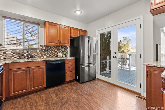 kitchen with black dishwasher, sink, stainless steel fridge, light stone countertops, and french doors