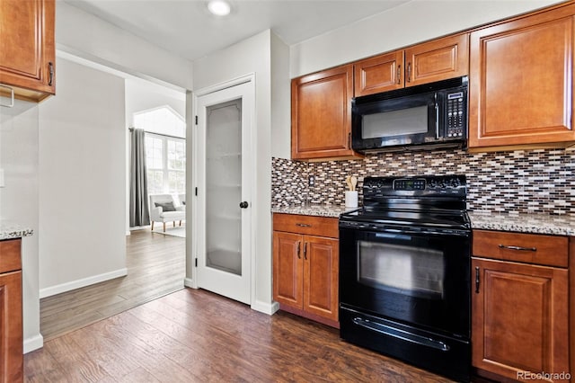 kitchen with light stone countertops, dark wood-type flooring, decorative backsplash, and black appliances