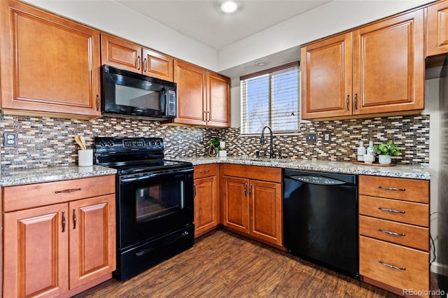 kitchen featuring sink, dark wood-type flooring, backsplash, light stone counters, and black appliances