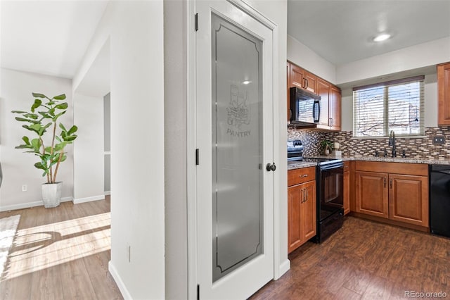 kitchen featuring sink, backsplash, dark hardwood / wood-style floors, and black appliances