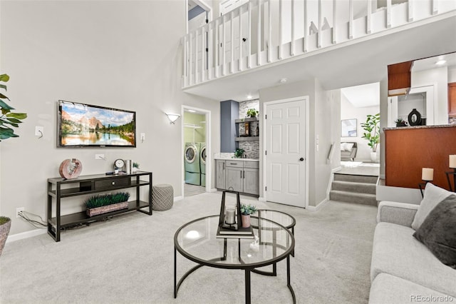 living room with a high ceiling, washing machine and dryer, and light colored carpet