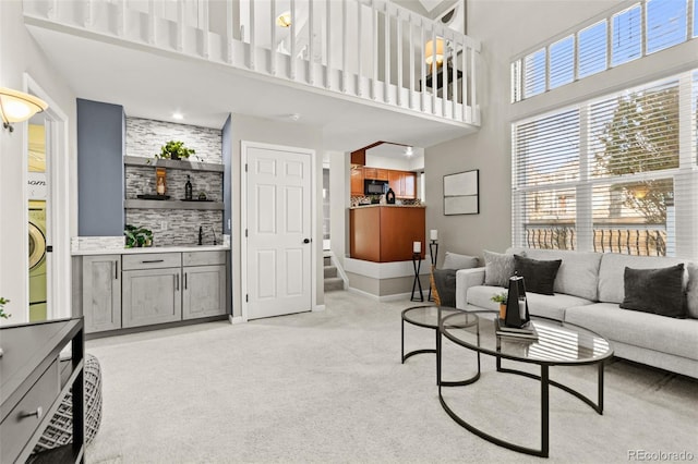 carpeted living room featuring washer / dryer and a towering ceiling