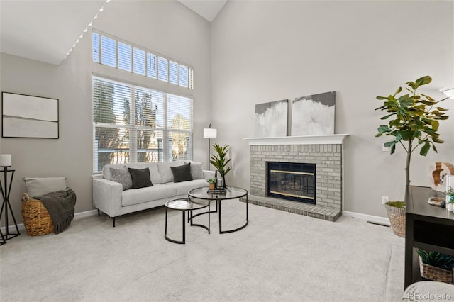 carpeted living room with a brick fireplace and a high ceiling