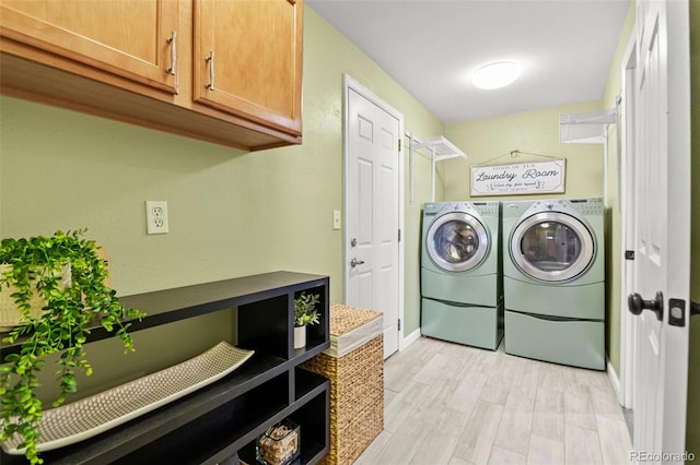 clothes washing area with cabinets, washer and dryer, and light wood-type flooring