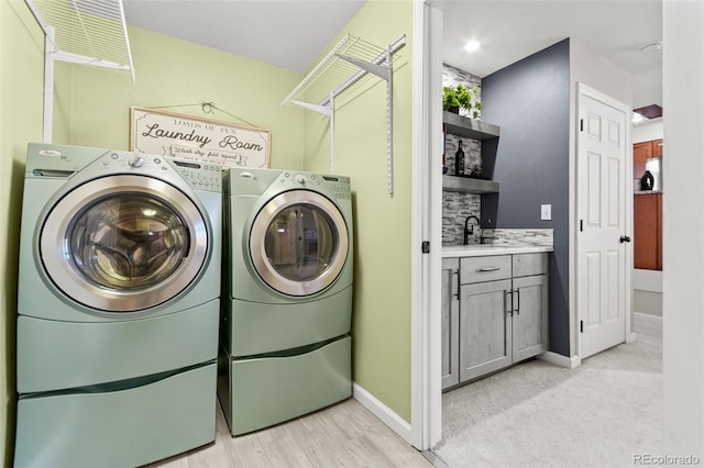 laundry room with sink, washing machine and clothes dryer, and light hardwood / wood-style floors