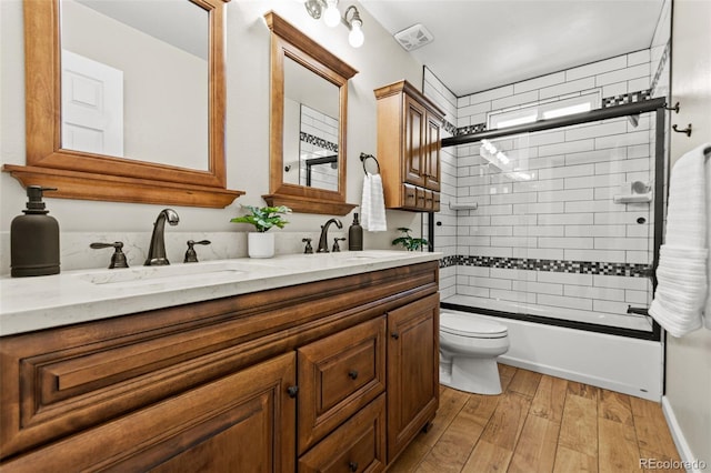 full bathroom featuring hardwood / wood-style flooring, vanity, combined bath / shower with glass door, and toilet