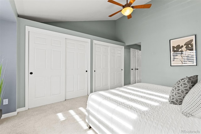 bedroom featuring lofted ceiling, ceiling fan, light colored carpet, and multiple closets