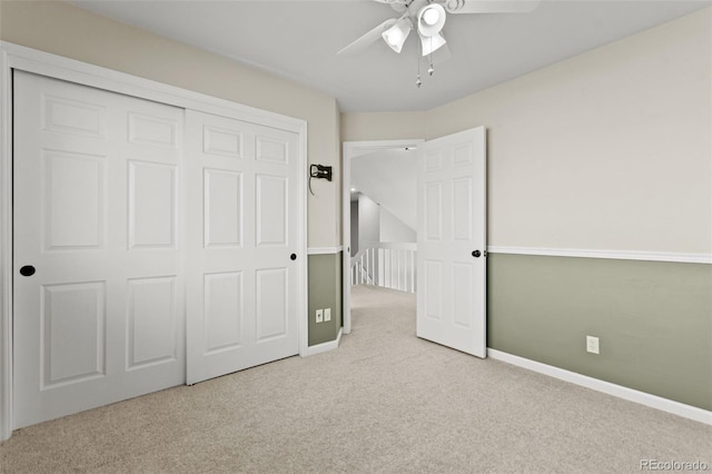 unfurnished bedroom featuring ceiling fan, a closet, and light carpet