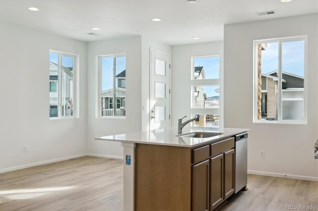 kitchen with dishwasher, a center island with sink, light hardwood / wood-style floors, and sink