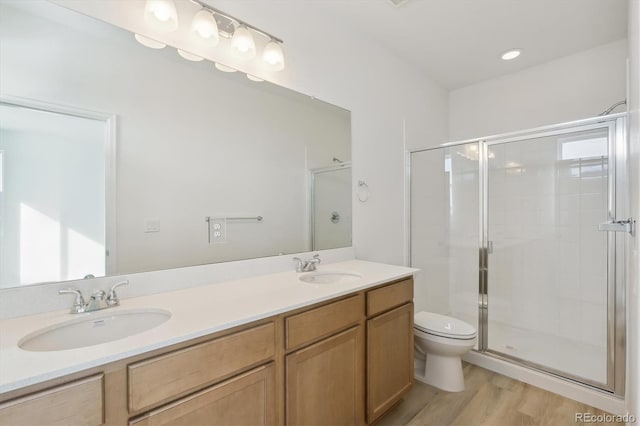 bathroom with wood-type flooring, vanity, toilet, and a shower with door