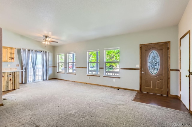 unfurnished living room featuring light carpet, a ceiling fan, and baseboards