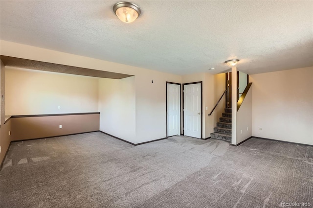 carpeted spare room featuring a textured ceiling, stairway, and baseboards
