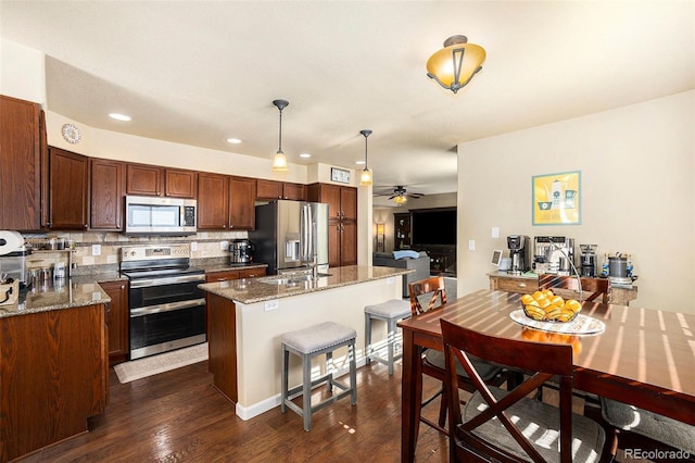 kitchen featuring a center island, stainless steel appliances, tasteful backsplash, hanging light fixtures, and light stone countertops