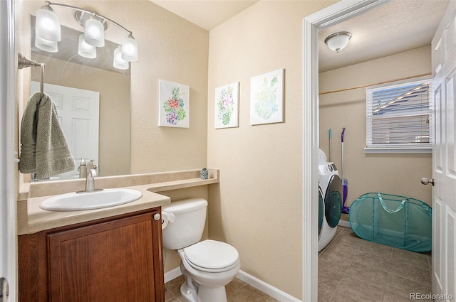 bathroom with toilet, vanity, washer / dryer, baseboards, and tile patterned floors