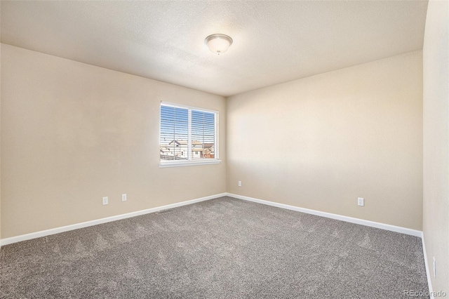 carpeted spare room with baseboards and a textured ceiling