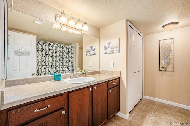 bathroom featuring baseboards, tile patterned flooring, a textured ceiling, vanity, and a closet