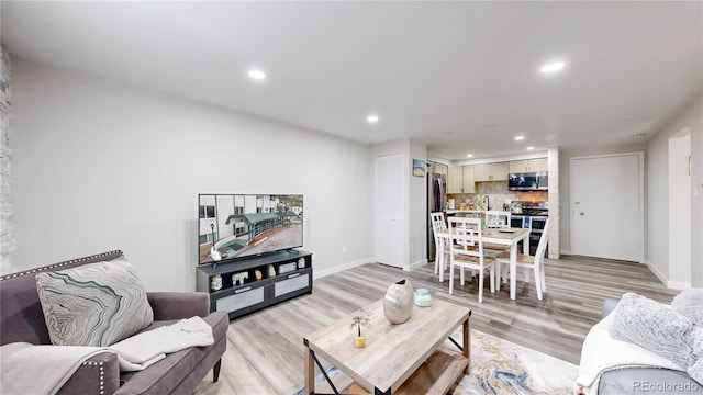 living room with baseboards, light wood-style flooring, and recessed lighting