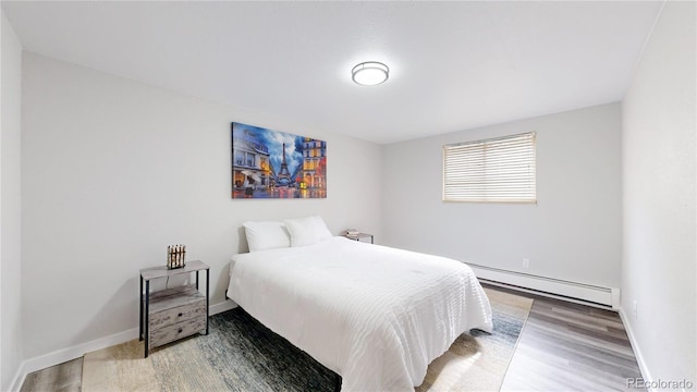 bedroom with a baseboard radiator, baseboards, and wood finished floors