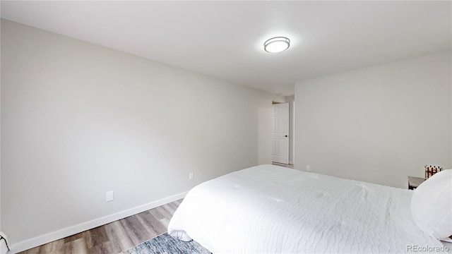 bedroom featuring baseboards and wood finished floors