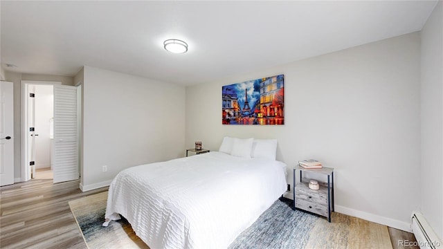 bedroom with baseboards, baseboard heating, and wood finished floors