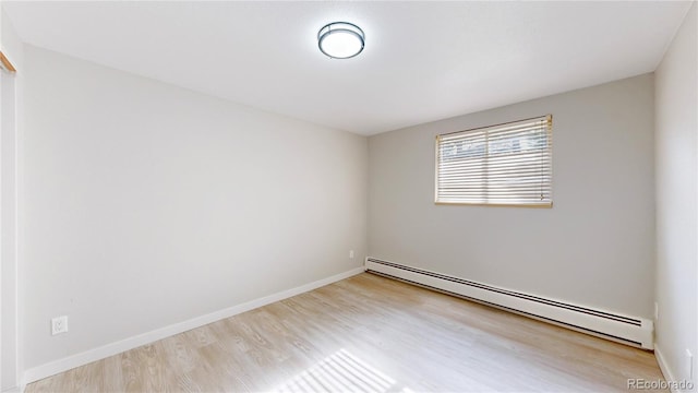 empty room with baseboards, baseboard heating, and wood finished floors