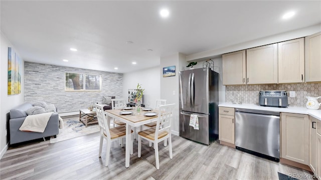 kitchen with light wood-style flooring, open floor plan, light countertops, appliances with stainless steel finishes, and decorative backsplash