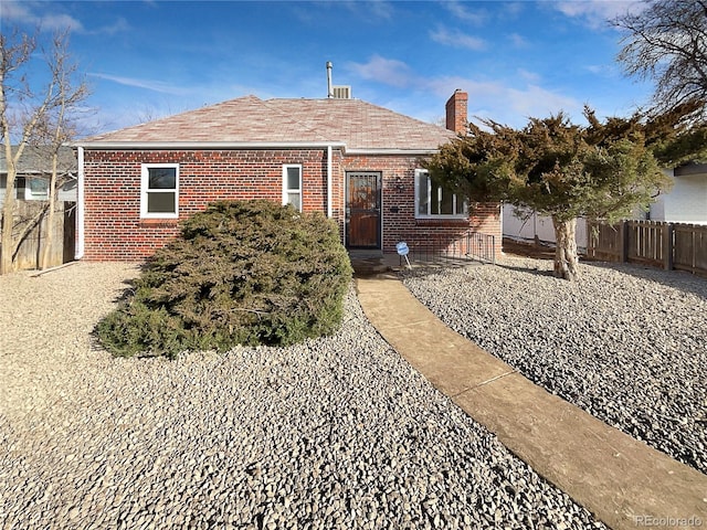 view of front of house with a chimney, fence, and brick siding