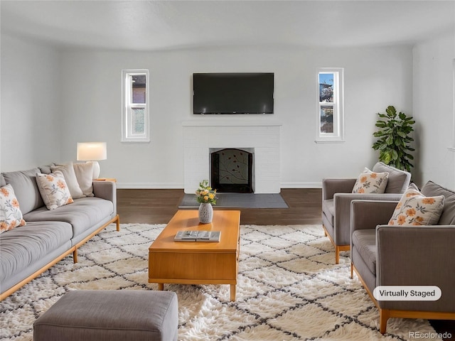 living area featuring a brick fireplace, wood finished floors, and baseboards