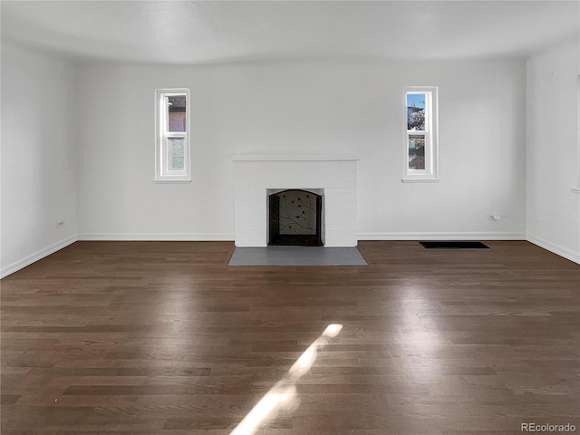 unfurnished living room with a healthy amount of sunlight, a fireplace, and wood finished floors