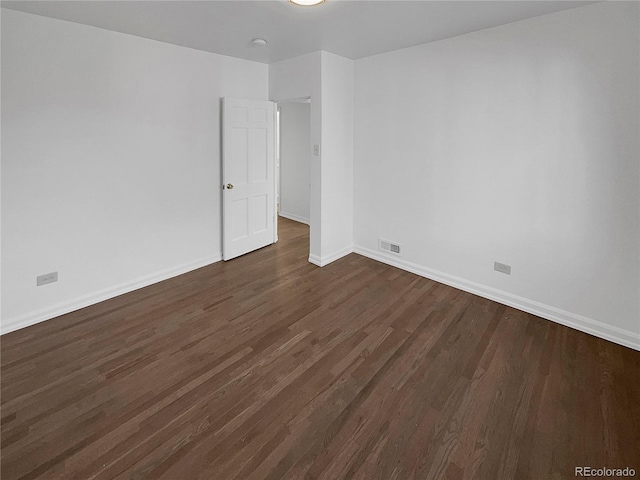 empty room with baseboards, visible vents, and dark wood-style flooring