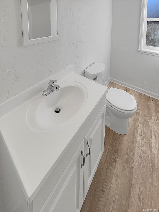 bathroom featuring toilet, wood finished floors, and vanity