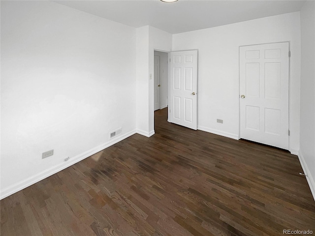 unfurnished bedroom with visible vents, dark wood finished floors, and baseboards