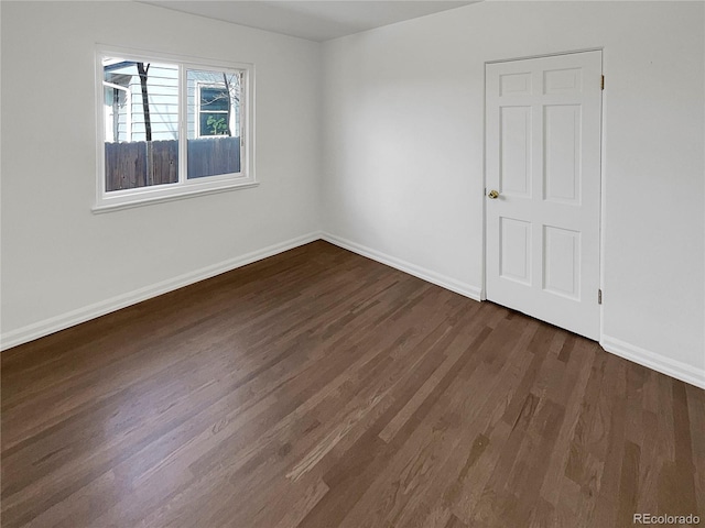 spare room featuring dark wood-type flooring and baseboards