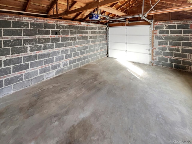 garage featuring concrete block wall and a garage door opener